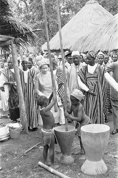 Queen Elizabeth watches two children grinding corn during a visit to Hangha in Kenema