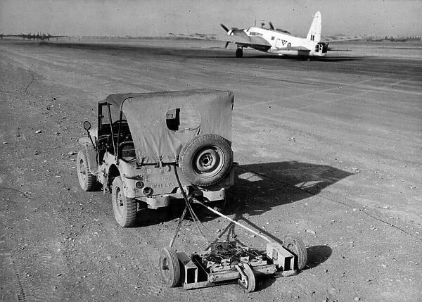 R. A. F. engineers search an airfield for mines using a magnetic sweep attached to a jeep