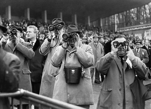 Racing at Sandown Park. Racegoes watching the action using binoculars January 1968
