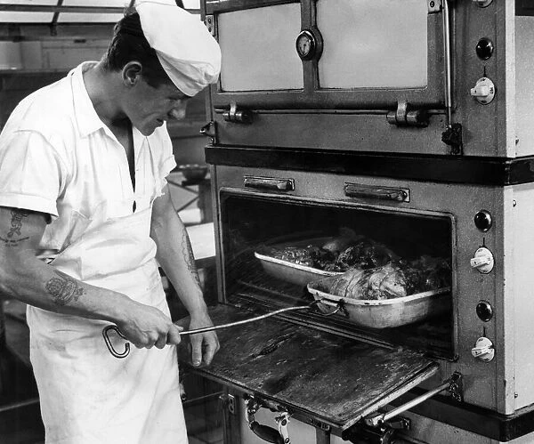 RAF Brawdy, Pembrokeshire, Wales. 14th July 1962. Cook J Green checks on the roast lamb