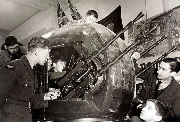 A RAF cadet explains the workings of the rear turret of a Halifax bomber to a group of