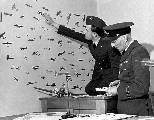 An RAF officer preparing cut outs of enemy planes from magazines to stick on the walls of