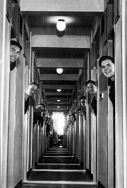 RAF recruits pop their heads out from the doorways of their new room-a-man quarters at