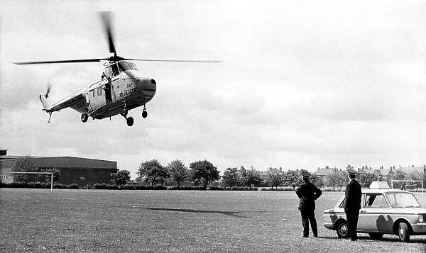 A RAF Westland Whirlwind search and rescue helicopter lands on a sportsfield next to two
