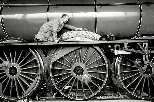 Railway worker cleans the sign on the wheels on the Flying Scotsman steam train