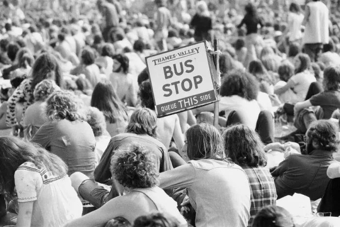 Framed Print : Reading Pop Festival. Festival goers with a Bus Stop sign watching the bands
