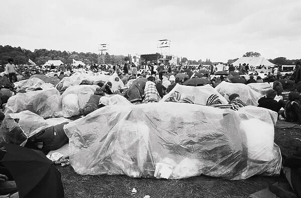 Reading Pop Festival. Festival goers covered in waterproof plastic sheets to