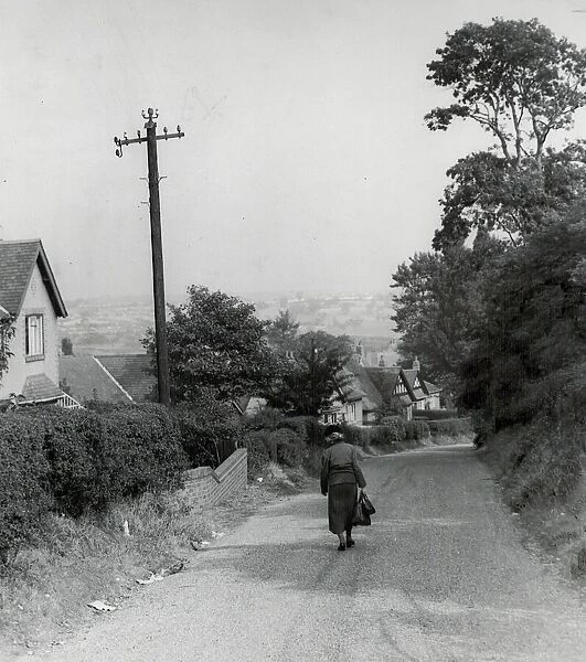 Rear view of a woman walking down a rural country lane near West Bromwich in the West