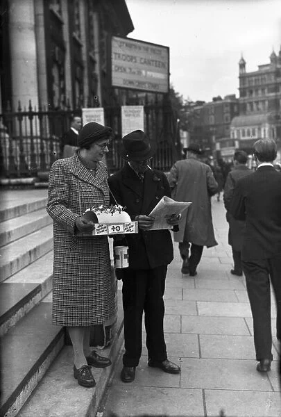 Red Cross flag seller in central London catches up on the latest news from Normandy