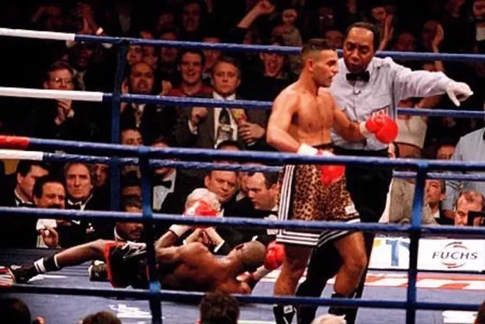 : The referee leads Prince Naseem Hamed to his corner after knocking Tom Boom Boom Johnson : The referee leads Prince Naseem Hamed to his corner after knocking Tom Boom Boom Johnson