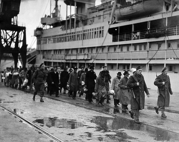 Refugees from Dutch colonies marching along the quayside under Dutch soldier escort