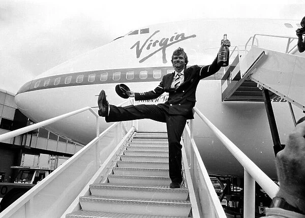 Richard Branson drinking from a bottle of champagne as he celebrates Virgin Atlantic