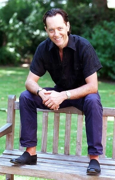Richard E Grant sitting on a bench August 1998 SOON TO APPEAR IN BBC TVs