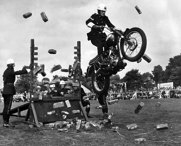 A rider of Royal Corps of Signals cycle display team crashes through a wall of bricks at