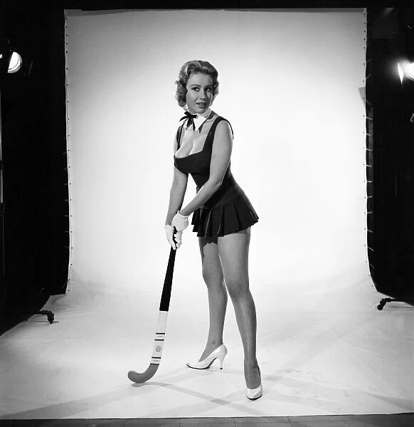 Rita Royce modelling sports kit with hockey stick. Circa 1959