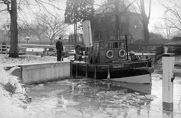 The river tug Thames makes its way through the frozen river Thames at Teddington
