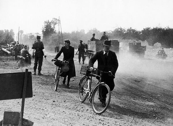 Road clearing in Normandy France, June 1944 French civilians pushing cycles passed
