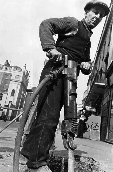 Road worker with drill taking up a street in London. 29th March 1935