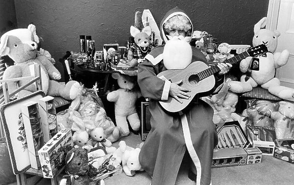 Rod Johnson, a guitar playing Father Christmas, surrounded by toys