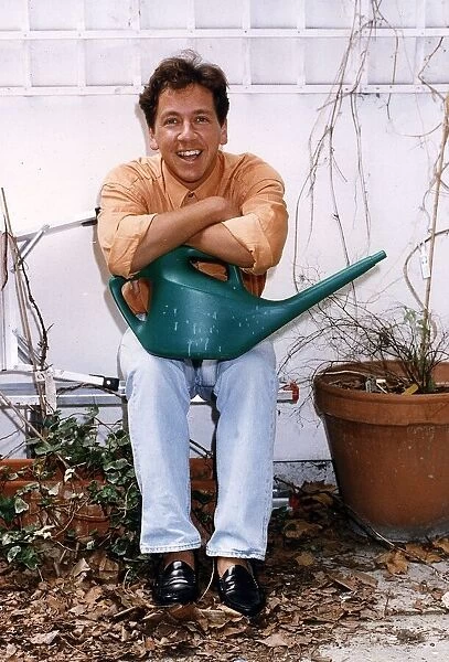 Ross King TV presenter in his garden holding a watering can