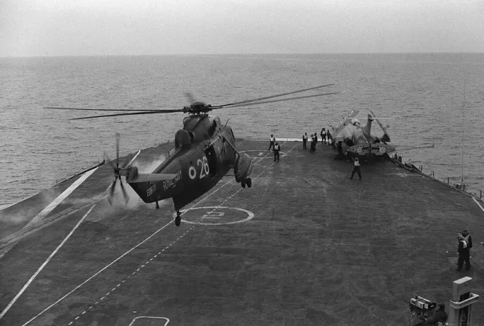 Framed Print : A Royal Navy Westland Sea King hovers over the deck as a Buccaneer with folded wings sits