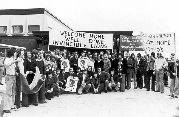 Rugby fans welcome the British Lions home to Heathrow. The banner on the right refers to