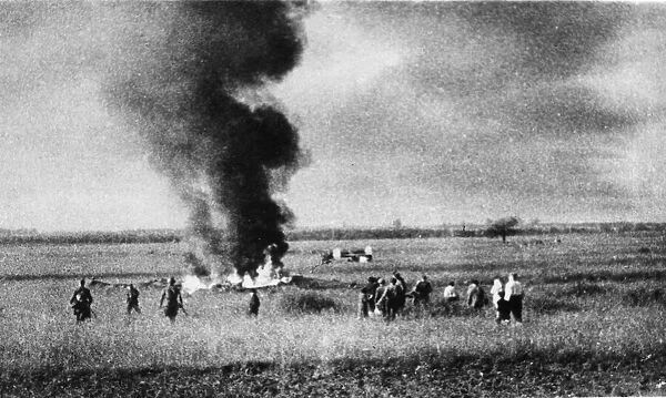 Russian soldiers and collective farmers watch the scattered remains of a German raiding