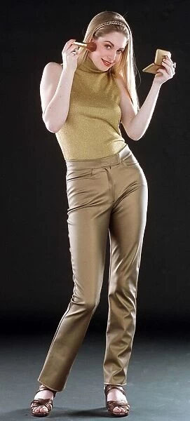 Ruth Kemmer model wearing gold trousers and top applying blusher to her face with a brush