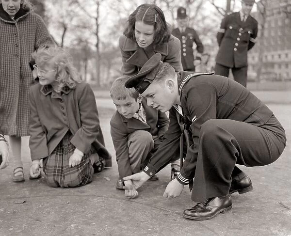 US Sailors in Hyde Park learning to play marbles March 1954