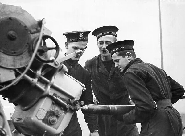 Three sailors manning a 3 inch anti-aircraft gun at gun practice on board the Polish Navy