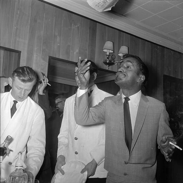 Sammy Davis Jnr at the Mayfair Hotel throws a paper in the air after reading