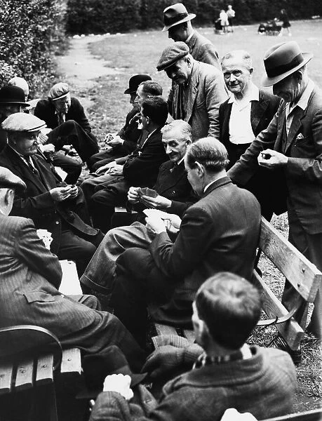 A scene in Clapham Park, a group men passing the time away playing cards