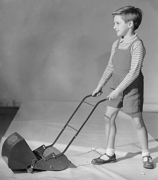 Schoolboy seen here playing with a toy lawn mower 2nd December 1957