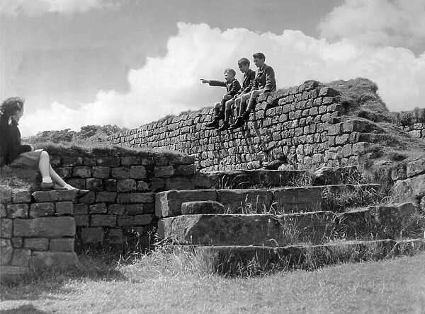 Schoolchildren sitting on the wall of the Roman Granary at Housesteads Fort in