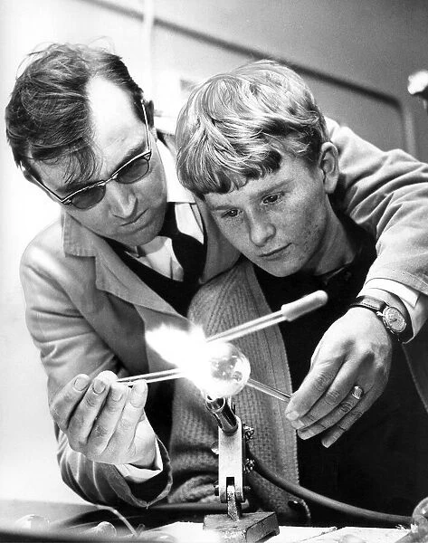 A scientific glass blower, Mr. Keith Hartley, instructs 17 year old Arthur Burdon in