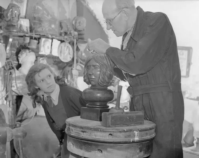 Framed Print : Sculptor William Snell seen here at work in his studio being watch by his schoolgirl