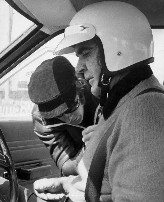 Framed Print : Sean Connery being strapped into motor car for lesson in grand prix driving