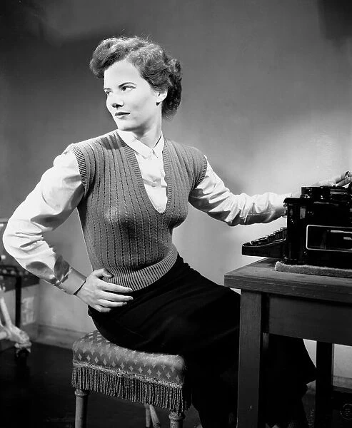 A secretary standing beside the typewriter in her office. June 1952