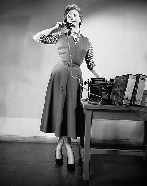A secretary talking on the telephone in the office. June 1952