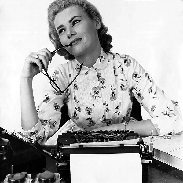 Secretary at typewriter chewing the end of her glasses daydreaming Typist