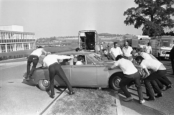 Set dressers move a Jaguar Mark II car for the next shot during location filming of