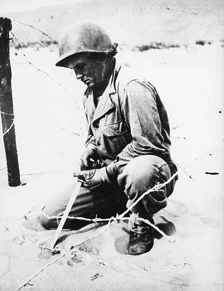 Sgt. Paul L. Feitag probes for mines with a bayonet in Italy. 23rd May 1944