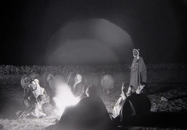 While Shepherds Watch Their Flocks By Night Shepherds gather around a camp fire