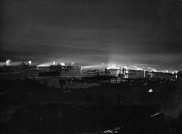 Ships searchlights illuminate Gibraltar Harbour at night during the Second World War
