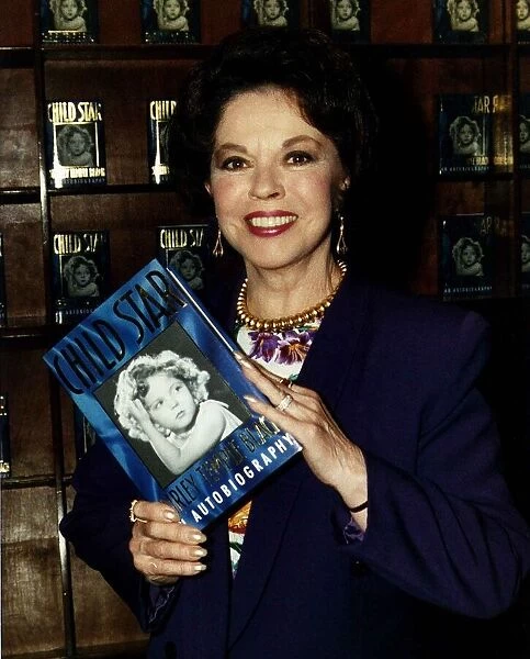Shirley Temple actress holding up a copy of her book Child Star May 1989