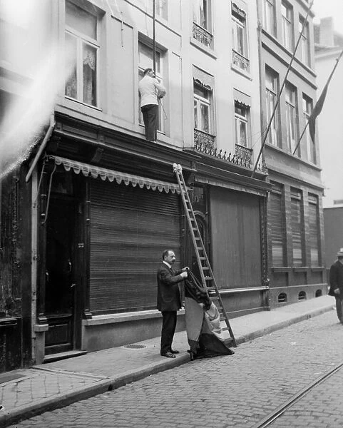 Shop owners taking down the Belgium flags before Louvain is occupied by the advancing