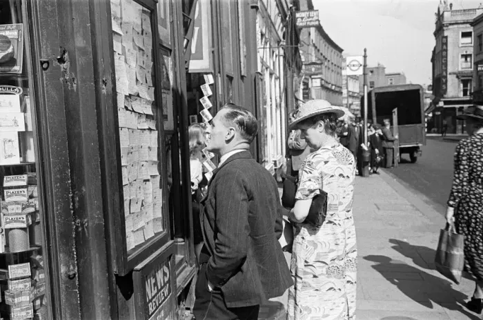Framed Print : Shoppers looking for a bargain read the small ads outside a Earls Court News Agents Framed Print : Shoppers looking for a bargain read the small ads outside a Earls Court News Agents