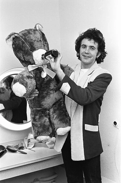 Singer and Actor David Essex poses with a teddy bear sent to him by a fan before going
