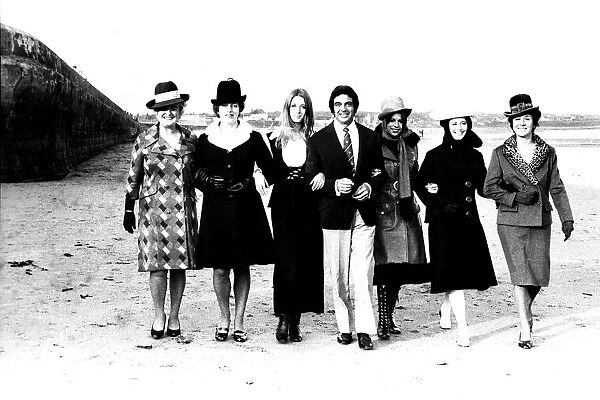 Singer Frankie Vaughan strolling along the beach with some of the models from a fashion