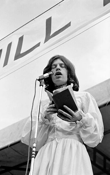 Singer Mick Jagger, wearing a white Mr Fish dress, reads the poem 'Adonais'